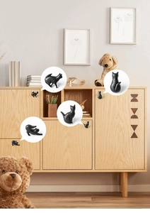 Close-up of matte black cast iron cat-shaped drawer handles on light wood furniture