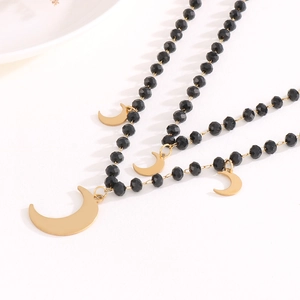 Detail of layered gold necklace featuring black faceted beads and crescent moon pendants