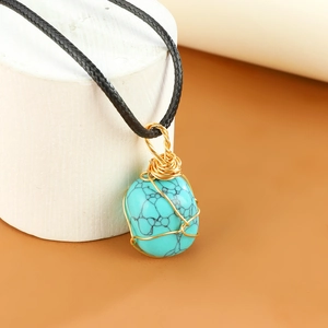 Detail van de turquoise hanger met gouden draadwikkeling aan een zwart gevlochten koord