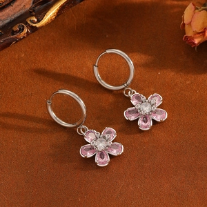 Détail de créoles argentées avec pendentifs fleurs roses et cristaux sur bois vintage