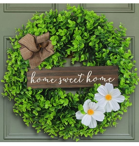 Detail of green boxwood wreath with home sweet home wood sign and white daisies