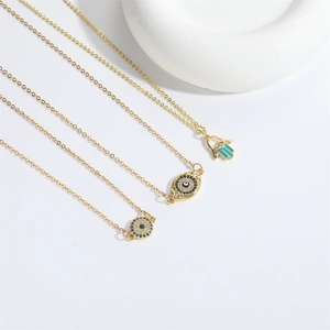 Detailed close-up of three gold Evil Eye and Hamsa Hand pendants on delicate chains