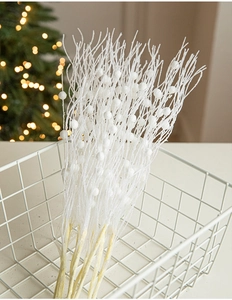 Close-up of frosted white Christmas berry picks with snow texture in a decorative basket