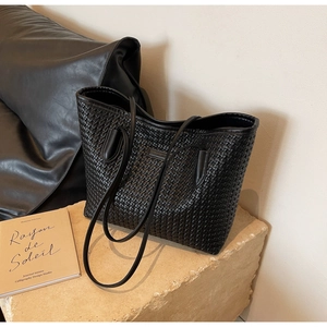 Detailed view of black woven PU leather tote bag with double handles on stone decor