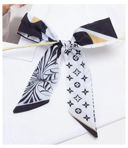 Detail of silk satin hair scarf featuring black and white monogram pattern and golden trim