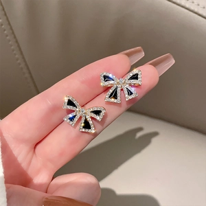 Detailed view of elegant black enamel bow earrings with gold plating and crystals