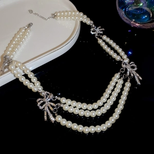 Detail showing elegant multi-layer pearl necklace with sparkling rhinestone bow clasp