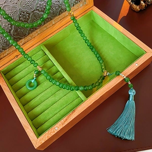 Gros plan d'un collier en jade vert avec pompon en soie dans un coffret en bois de luxe