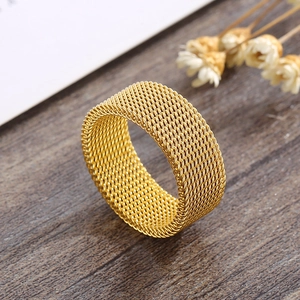 Close-up of golden mesh band ring showing intricate woven texture on dark wood background