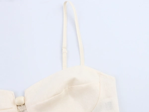 Detail of adjustable straps and bead button on beige linen blend vacation crop top