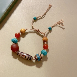 Detailed view of ethnic bracelet with agate, turquoise, and Dzi beads on woven cord