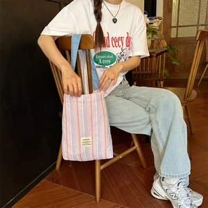 Gros plan d'un sac cabas en toile rayée rose et bleu avec étiquette de marque tissée
