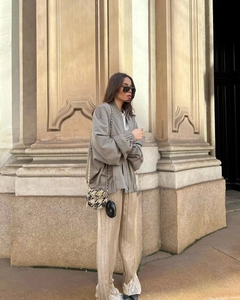 Detailed outdoor shot of a casual grey bomber jacket and pleated champagne trousers