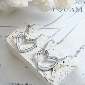 Sleek silver hollow heart pendant necklace set on minimalist stone textured background