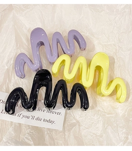 Close-up of three jelly-colored wavy hair claws in purple, yellow, and black colors