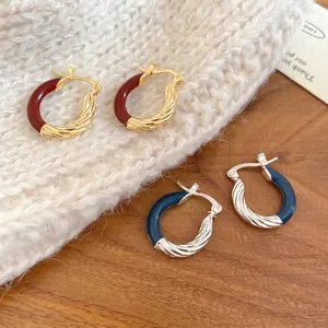 Twisted gold and silver hoop earrings with deep red and blue enamel glaze textures
