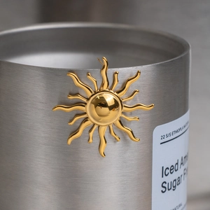Minimalist 18K gold plated stainless steel sunburst stud earrings on a metal cup
