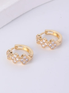 Close-up of gold-plated huggie earrings featuring three crystal-paved clover motifs