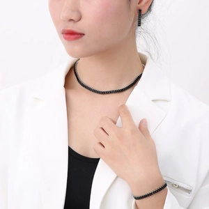 Detail shot of a woman wearing a black zircon necklace, bracelet and earrings set