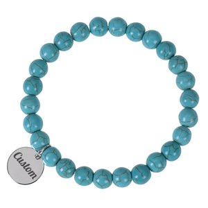 Detail of turquoise beaded bracelet featuring a custom engraved silver metal round pendant