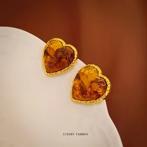 Vintage heart-shaped amber resin earrings with hammered gold metal texture on a tray