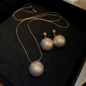 Parure collier et boucles d'oreilles en perles champagne sur écrin noir chic