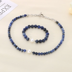 Detail view of blue beaded necklace and bracelet set with white pearl and silver OT clasp