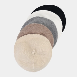 Stack of five stylish knitted beret hats in beige tan grey white and black