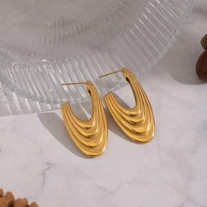 Boucles d'oreilles U en acier inoxydable doré posées sur marbre blanc chic