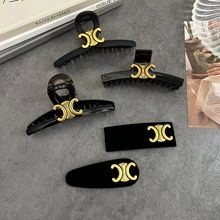Detail of five-piece hair clip set in black and brown with golden triomphe emblems