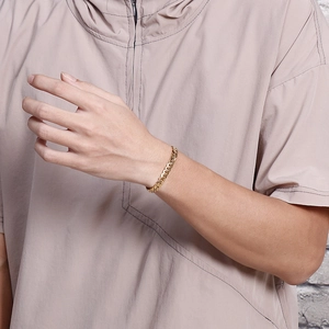 Close-up of a gold minimalist flat Cuban link chain bracelet worn on a woman's wrist