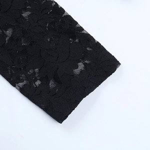 Close-up of black floral lace texture on the long sleeves of a sexy polo top