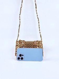 Detail view of handmade gold beaded crossbody bag with a smartphone inside for size comparison