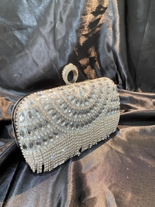Close-up of silver rhinestone evening bag featuring teardrop crystals and fringe details