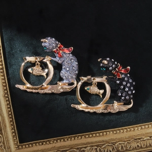 Detail of cat and goldfish bowl brooches with rhinestones on green velvet background