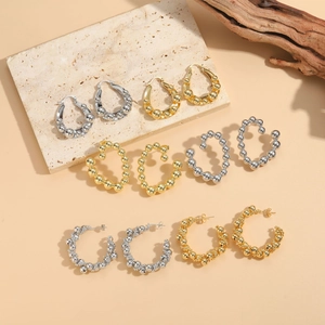 Detailed selection of gold and silver beaded hoop earrings on a textured stone surface