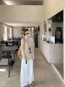 Two-piece beige sun protection top set styled with wide-leg pants and woven bag