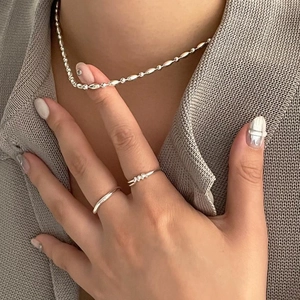 Detailed view of 925 sterling silver beaded necklace and minimalist rings on a model