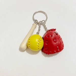 Close-up of baseball keychain with mini wooden bat, yellow ball, and red leather glove