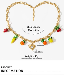 Detail of gold fruit charm necklace with strawberry and lemon pendants on thick link chain