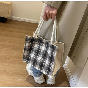 Detail of checkered canvas tote bag with beige linen sides and white rope handles