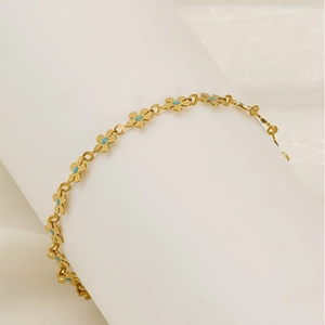 Elegant gold flower bracelet with turquoise centers on a white display stand