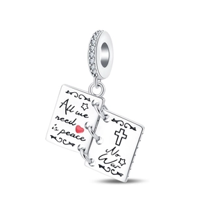 Macro detail of silver charm engraved with All we need is peace and a red heart