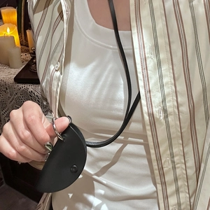 Close-up of a vintage black semi-circle leather pendant pouch necklace with snap button