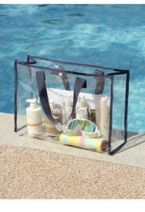 Transparent waterproof beach bag with blue trim holding toiletries by the pool side