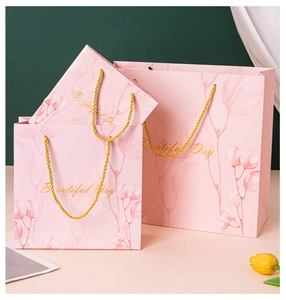 Detailed view of pink gift bags with gold handles and floral botanical prints