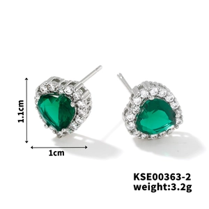 Macro shot of heart-shaped green emerald stud earrings with tiny white diamonds and silver base