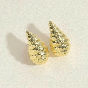 Macro view of gold seashell-shaped earrings with textured metallic surface and luster