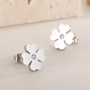 Macro shot of silver metal four-leaf clover earrings with a central clear zircon inlay