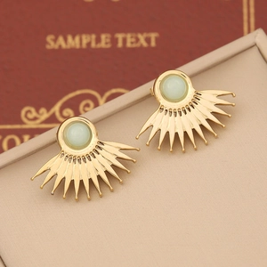 Detailed close-up of sunburst stud earrings featuring a green stone in a gold setting